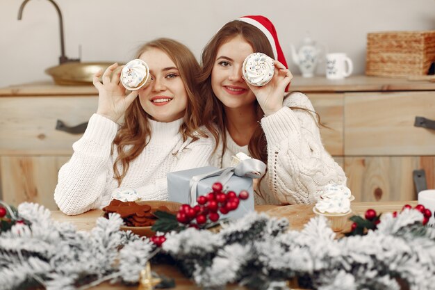 Las mujeres tienen cupcakes. Amigos en una decoración navideña. Chica con sombrero de Santa.