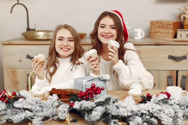 Las mujeres tienen cupcakes. Amigos en una decoración navideña. Chica con sombrero de Santa.