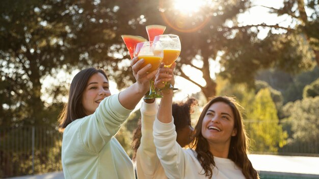 Las mujeres tintinean vasos de tiro medio