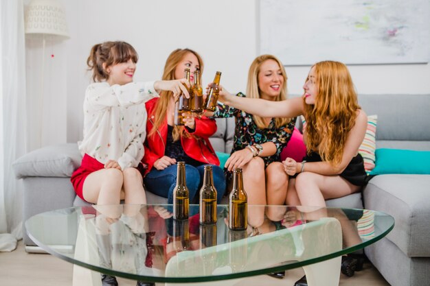 Mujeres tintineando cerveza en casa