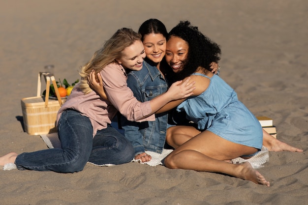 Mujeres de tiro completo abrazándose en la playa