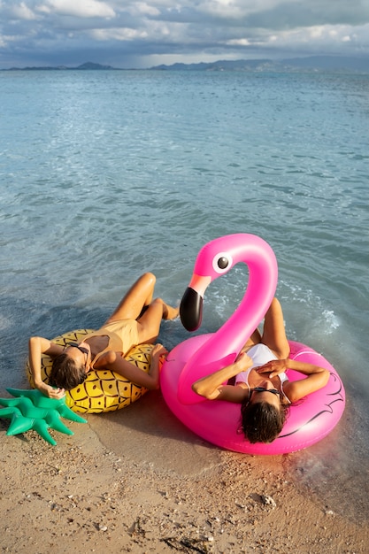 Mujeres de tiro completo acostadas en flotadores