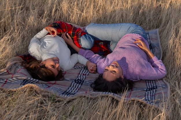 Foto gratuita mujeres de tiro completo acostadas sobre una manta al aire libre