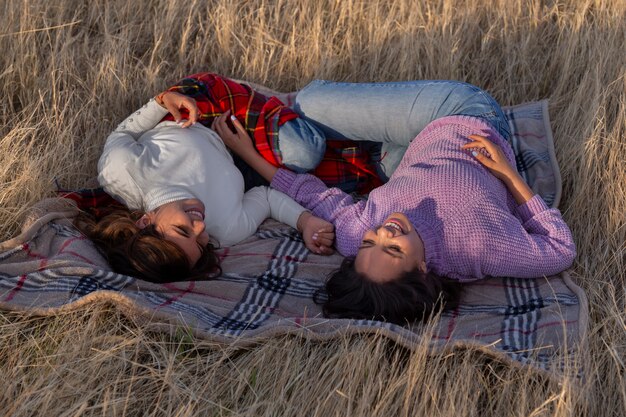 Mujeres de tiro completo acostadas sobre una manta al aire libre