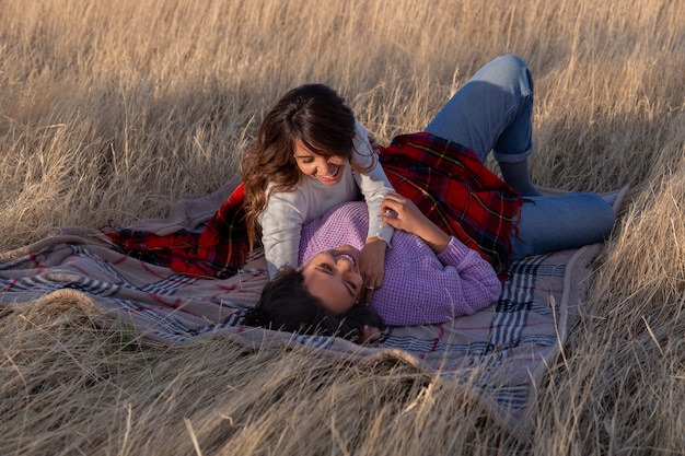 Foto gratuita mujeres de tiro completo acostadas sobre una manta al aire libre