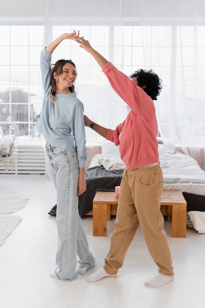 Mujeres de tiro completo bailando en casa.