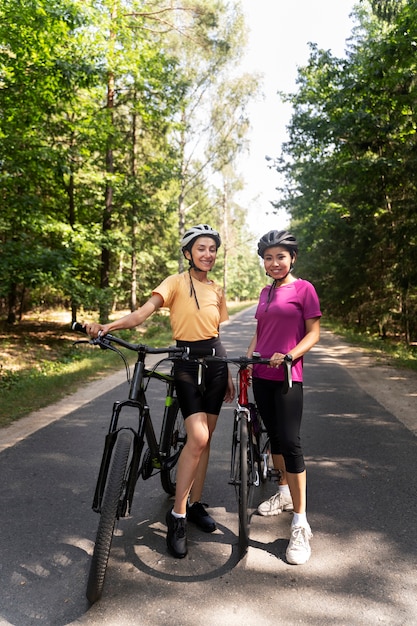 Mujeres de tiro completo con bicicletas en la calle.