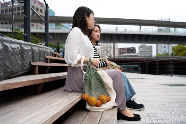 Mujeres de tiro completo con bolsas de tela.