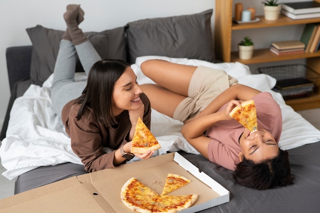 Foto gratuita mujeres de tiro completo comiendo deliciosa pizza