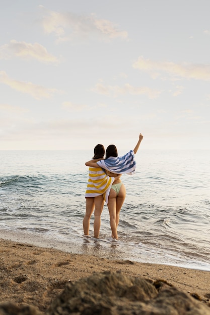 Foto gratuita mujeres de tiro completo divirtiéndose en la playa