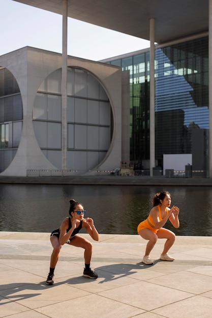 Mujeres de tiro completo haciendo sentadillas al aire libre