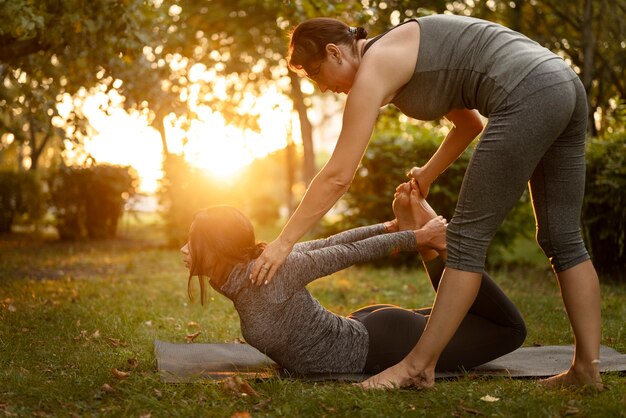 Mujeres de tiro completo haciendo yoga al aire libre