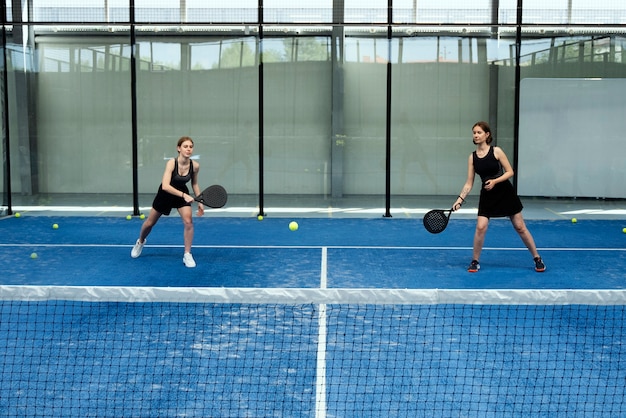 Mujeres de tiro completo jugando al pádel.