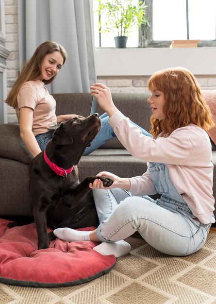 Mujeres de tiro completo jugando con perro