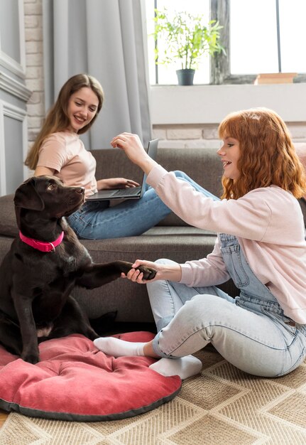 Mujeres de tiro completo y lindo perro