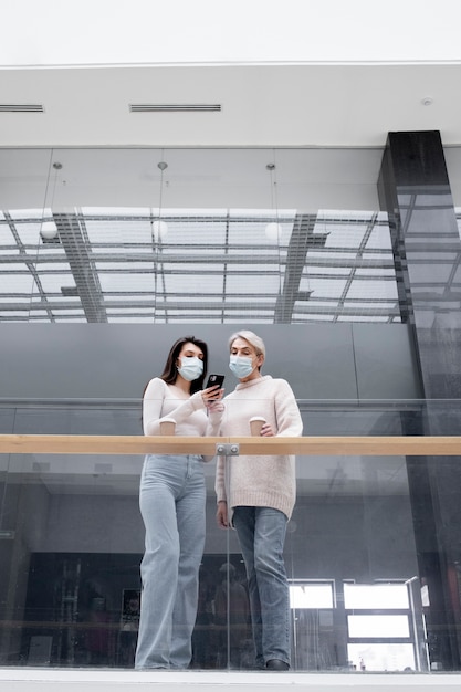 Foto gratuita mujeres de tiro completo mirando el teléfono inteligente