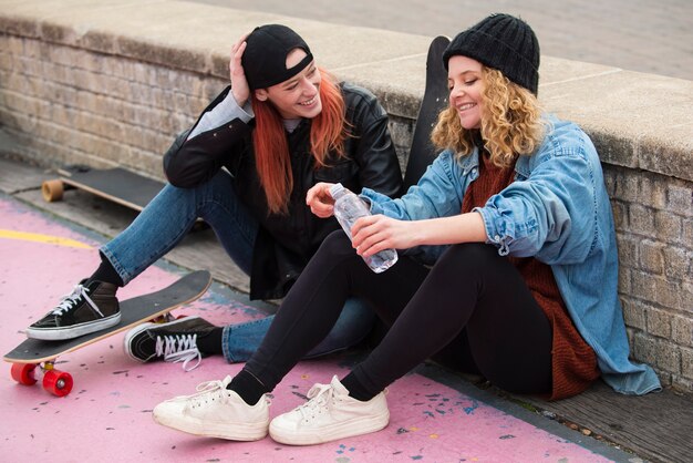 Mujeres de tiro completo con patinetas.