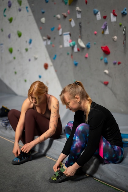 Mujeres de tiro completo preparándose para escalar la pared