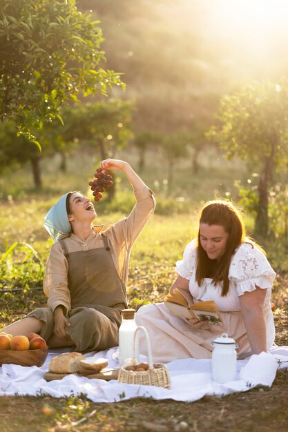 Mujeres de tiro completo sentadas juntas en un picnic