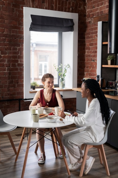 Foto gratuita mujeres de tiro completo sentadas en la mesa