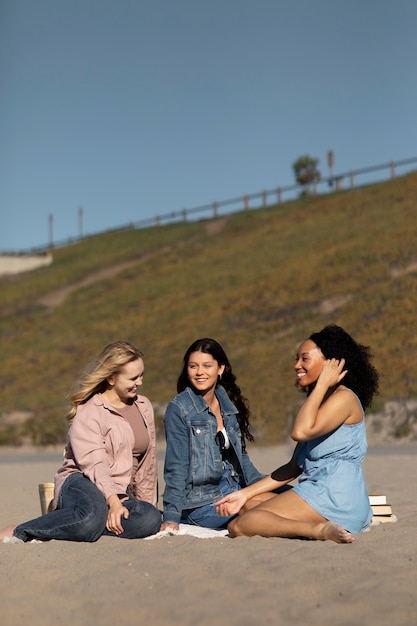 Mujeres de tiro completo sentadas en la playa