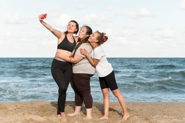 Mujeres de tiro completo tomando selfies juntas
