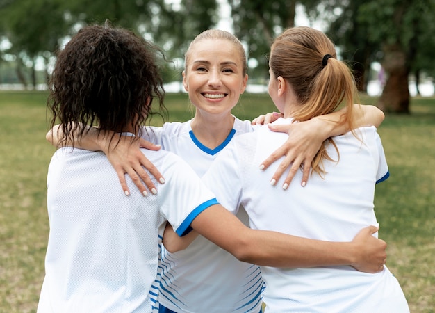 Mujeres de tiro medio abrazándose afuera