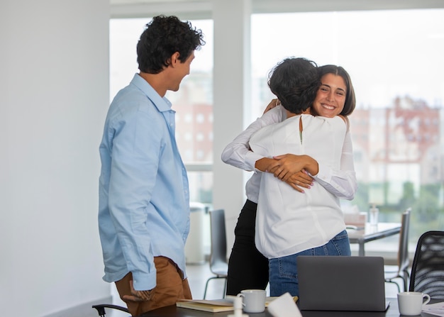 Mujeres de tiro medio abrazándose en el trabajo