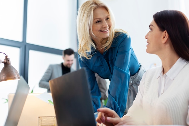 Mujeres de tiro medio chateando en el trabajo