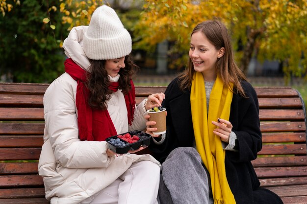 Mujeres de tiro medio con deliciosas bayas en el parque.