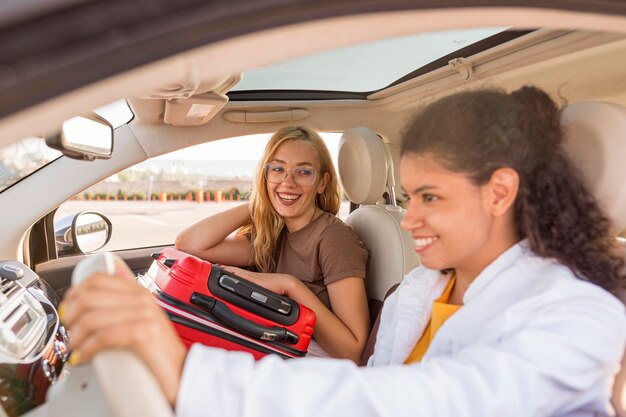 Mujeres de tiro medio con equipaje en coche