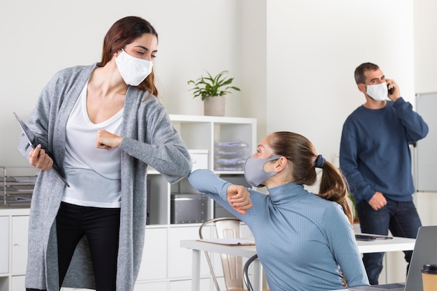 Mujeres de tiro medio golpeando el codo