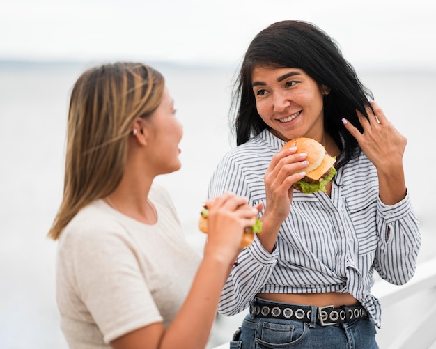 Mujeres de tiro medio con hamburguesas