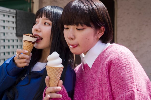 Mujeres de tiro medio lamiendo conos de helado