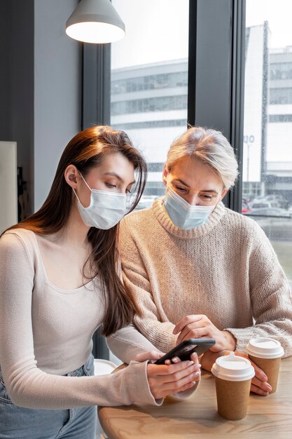 Mujeres de tiro medio con mascarillas en interiores