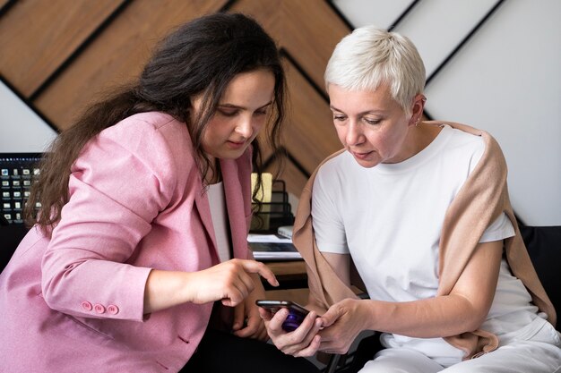 Mujeres de tiro medio mirando smartphone