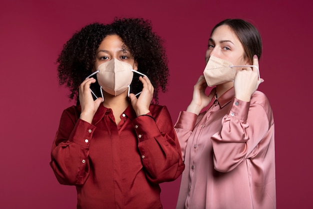 Foto gratuita mujeres de tiro medio poniéndose mascarillas