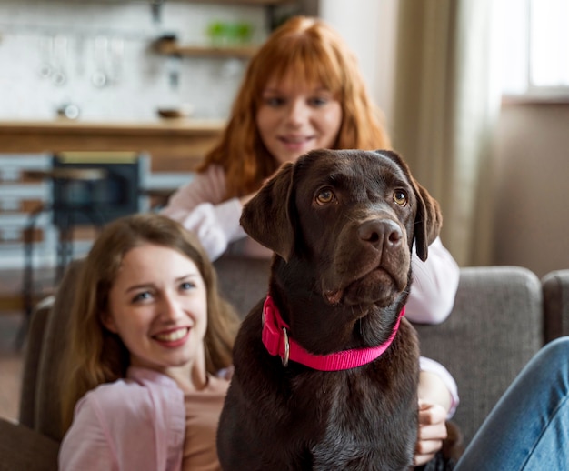 Mujeres de tiro medio posando con perro