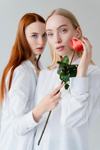 Mujeres de tiro medio posando con rosa