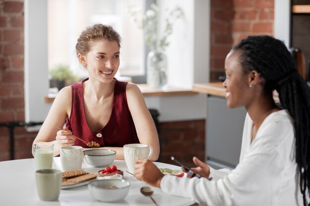 Mujeres de tiro medio sentadas en la mesa