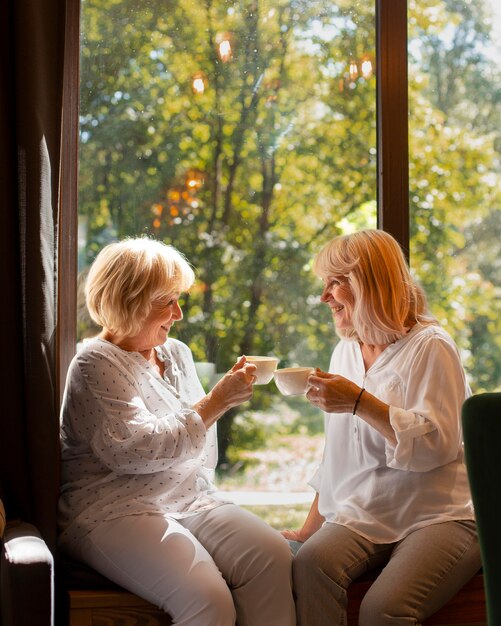 Mujeres de tiro medio sosteniendo tazas