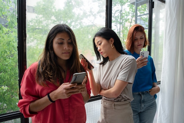 Mujeres de tiro medio con teléfono inteligente en interiores.