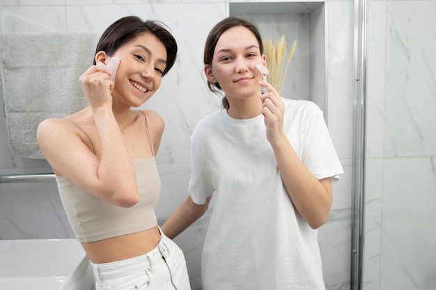 Mujeres de tiro medio usando herramientas gua sha