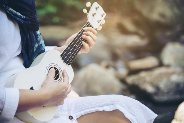 Las mujeres tocan el ukelele nuevo a la cascada.