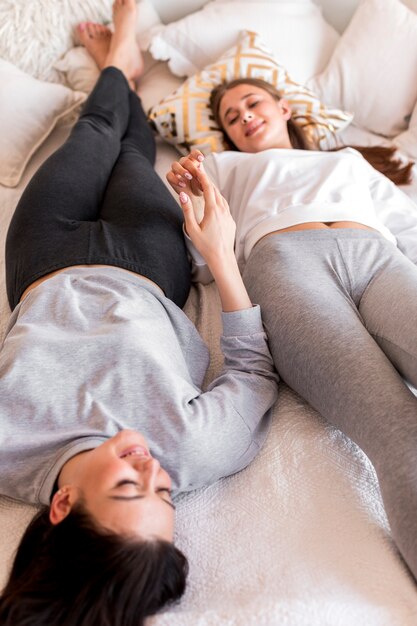 Mujeres tocando las manos mientras yacen en la cama