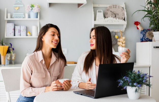 Mujeres tomando café y mirando portátil