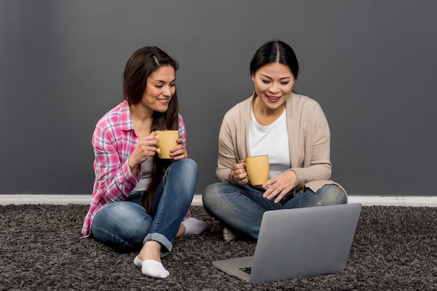 Mujeres tomando café y usando laptop