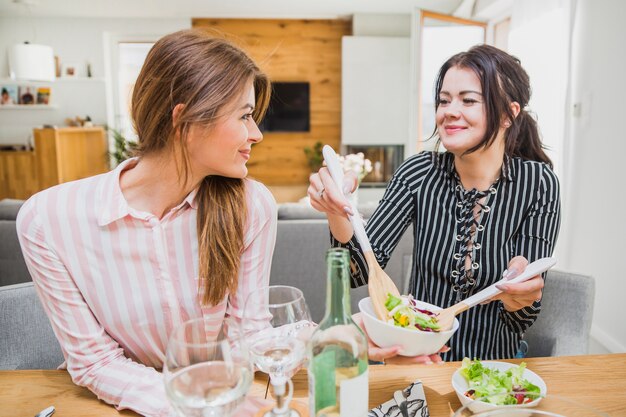 Mujeres tomando ensalada con cucharas de madera