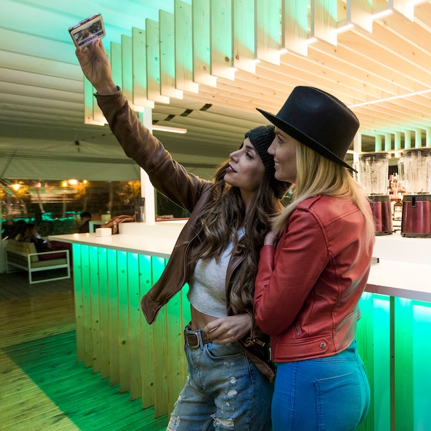 Mujeres tomando selfie cerca de la barra