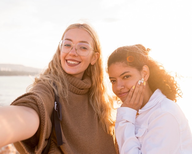 Foto gratuita mujeres tomando selfies en la playa.